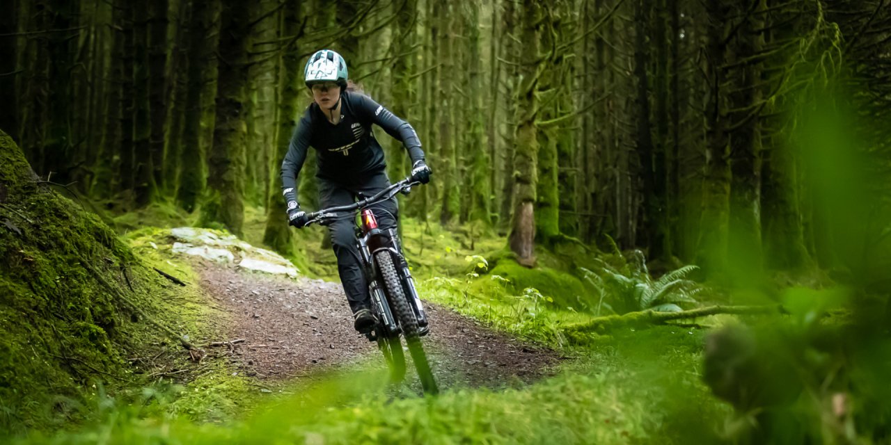 Boy riding a bike along a trail in a green forest